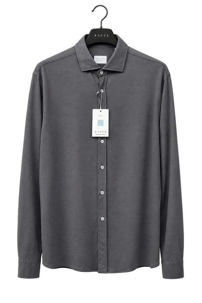 A dark gray long-sleeve button-up shirt by Sacor, hanging on a black hanger against a bright yellow wall. The shirt has a white product tag attached to the collar.