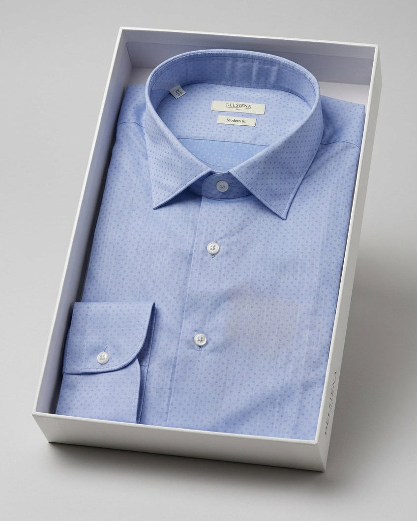 A light blue micro-patterned dress shirt folded inside a white presentation box, photographed on a clean light gray background.